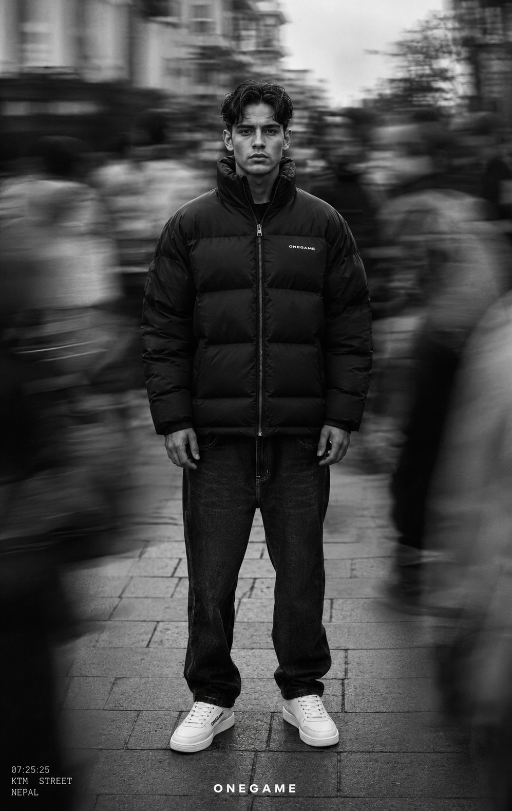Man in a black puffer jacket standing still in a blurred city street.